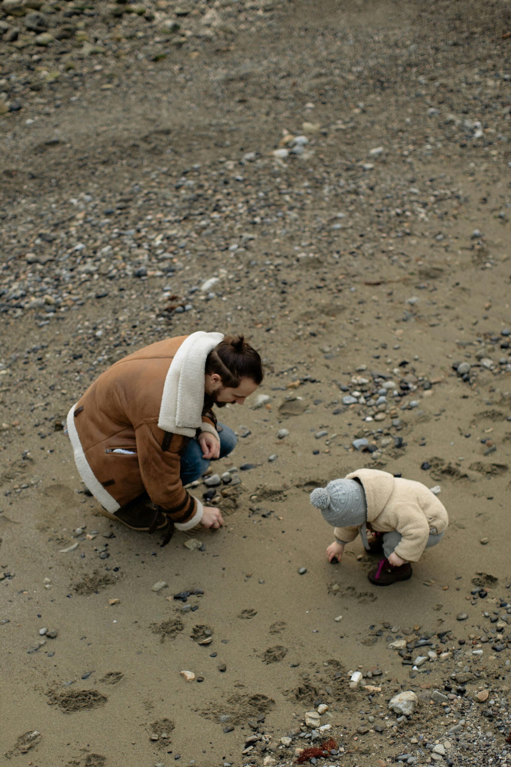 Man with child on a beach picking up shells. Rediscover prayer in ordinary moments.